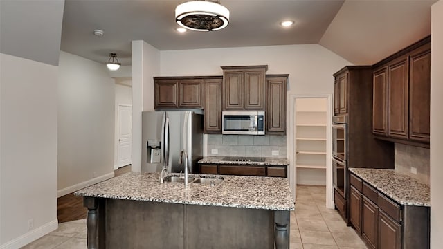 kitchen featuring appliances with stainless steel finishes, sink, light stone counters, and dark brown cabinets