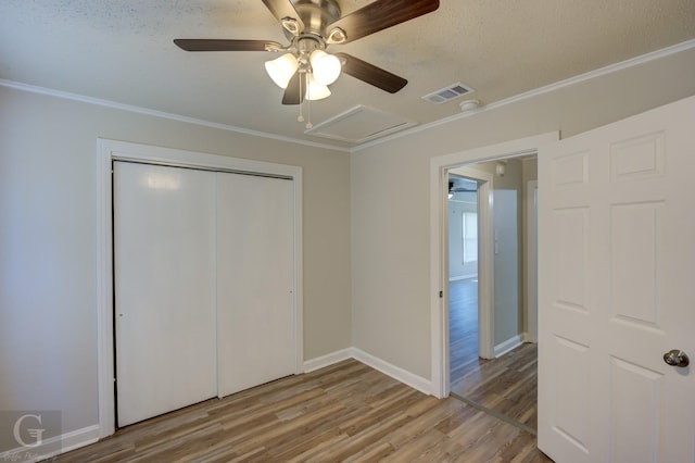 unfurnished bedroom with hardwood / wood-style flooring, ornamental molding, a closet, and ceiling fan