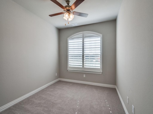 empty room featuring light carpet, ceiling fan, visible vents, and baseboards