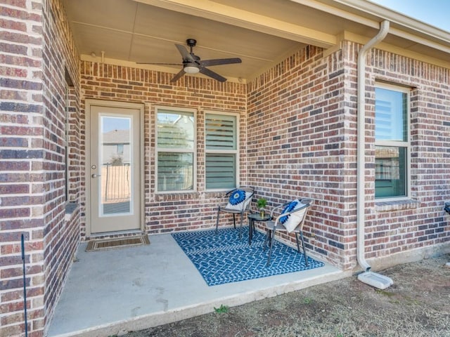 doorway to property featuring a ceiling fan, a patio area, and brick siding