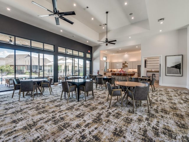 carpeted dining area with a high ceiling and ceiling fan