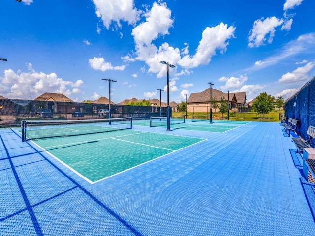 view of tennis court with fence and a residential view