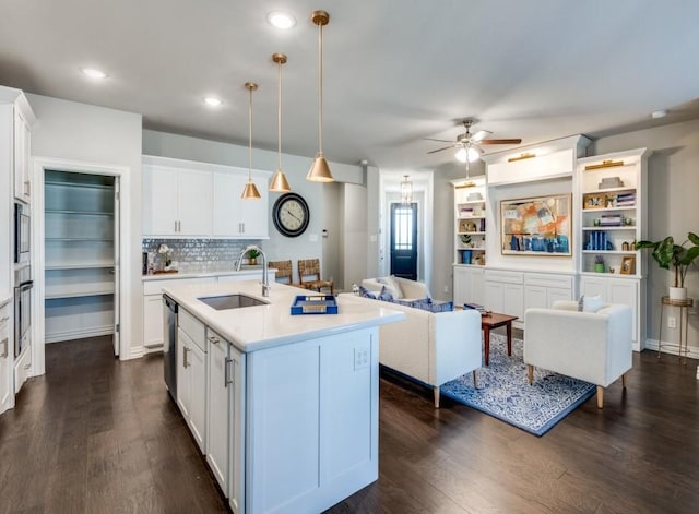 kitchen featuring white cabinets, sink, a kitchen island with sink, and decorative light fixtures