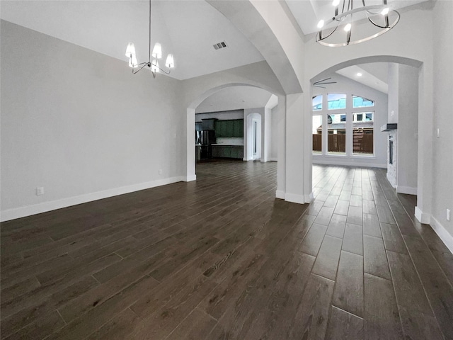 interior space with vaulted ceiling, ceiling fan with notable chandelier, and dark hardwood / wood-style flooring