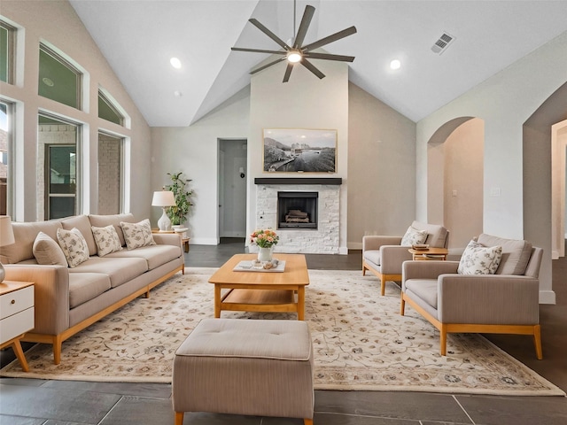 living room with wood-type flooring, a stone fireplace, and high vaulted ceiling