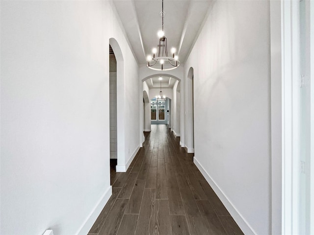 corridor featuring dark hardwood / wood-style floors and an inviting chandelier