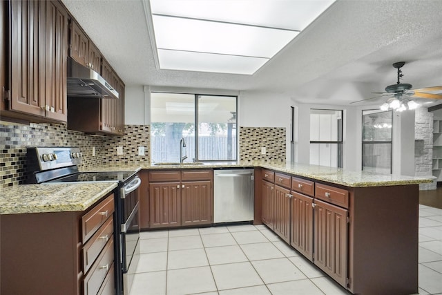 kitchen featuring sink, decorative backsplash, kitchen peninsula, stainless steel appliances, and light stone countertops