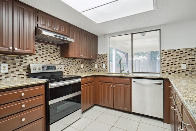 kitchen with tasteful backsplash, sink, light tile patterned floors, light stone counters, and stainless steel appliances