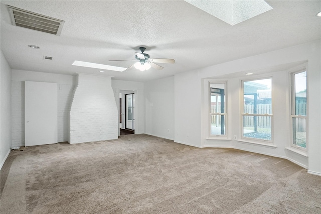 carpeted spare room with ceiling fan, a skylight, and a textured ceiling