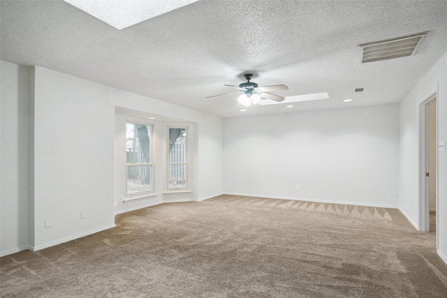 carpeted empty room with a textured ceiling, ceiling fan, and a skylight