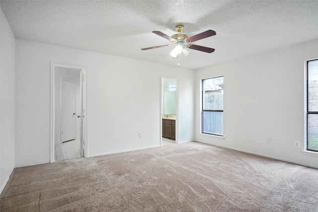 carpeted spare room with ceiling fan, plenty of natural light, and a textured ceiling