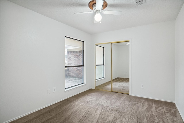 unfurnished bedroom featuring ceiling fan, carpet floors, a closet, and a textured ceiling