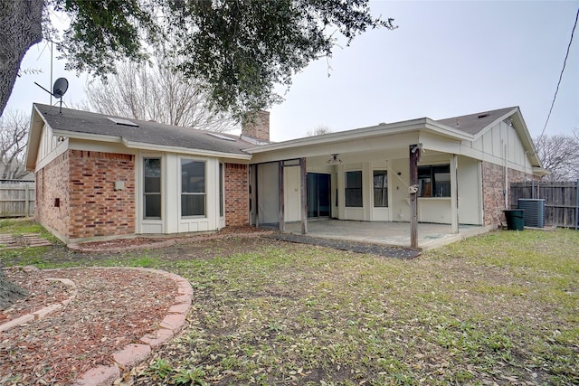 rear view of property featuring a yard, central AC unit, and a patio area