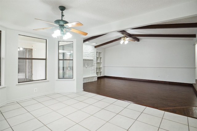 empty room with ceiling fan, vaulted ceiling with beams, light tile patterned floors, and a textured ceiling