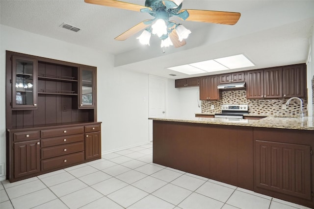 kitchen featuring sink, a skylight, light stone countertops, stainless steel electric range oven, and kitchen peninsula