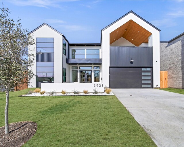 contemporary home with a garage, stucco siding, concrete driveway, and a front yard