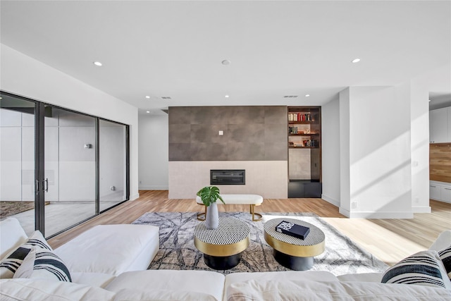 living area featuring light wood-style flooring, recessed lighting, and a tile fireplace