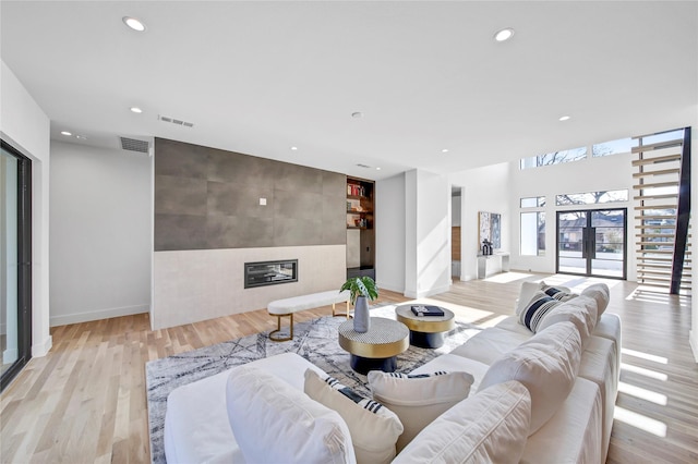 living room featuring french doors, a tiled fireplace, and light hardwood / wood-style floors