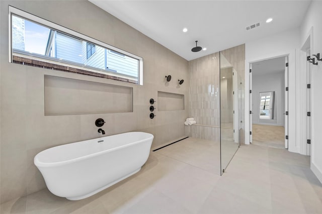 bathroom with separate shower and tub, tile walls, and tile patterned floors