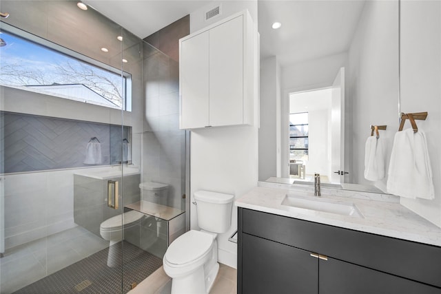 bathroom featuring tile patterned flooring, vanity, an enclosed shower, and toilet