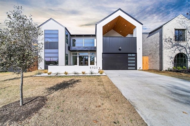 contemporary home featuring a garage, a balcony, and a front lawn