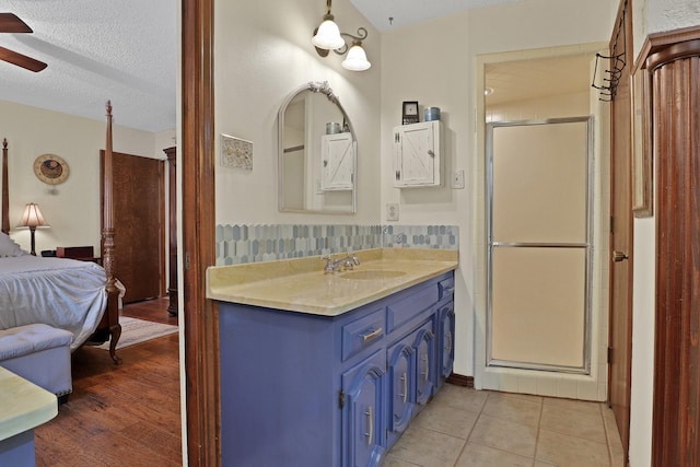 bathroom featuring tile patterned flooring, vanity, ceiling fan, a shower with door, and a textured ceiling