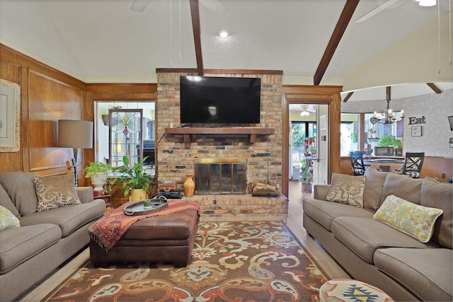 living room featuring a brick fireplace, ceiling fan with notable chandelier, lofted ceiling with beams, and wood walls