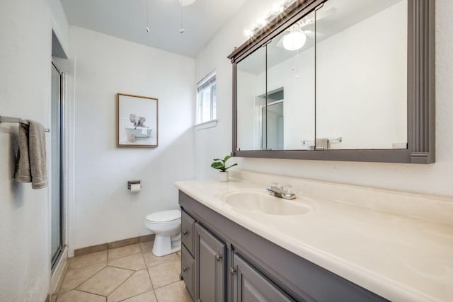 bathroom with toilet, a stall shower, vanity, baseboards, and tile patterned floors