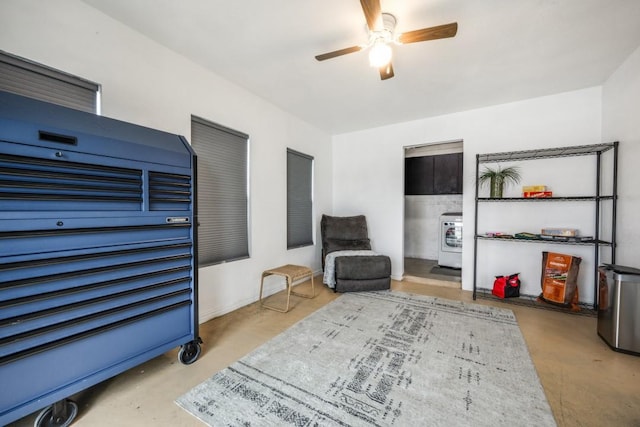 living area featuring washer / dryer, finished concrete floors, and a ceiling fan