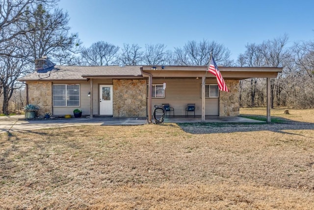 view of front of property with stone siding, a front lawn, and a chimney