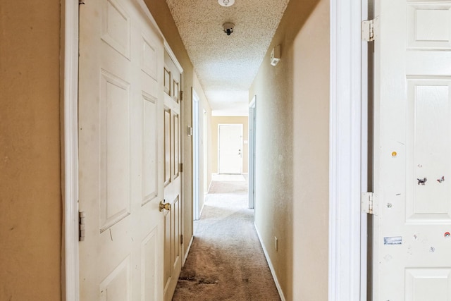 hallway with carpet flooring and a textured ceiling