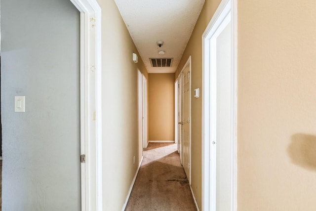 corridor with light carpet and a textured ceiling