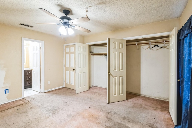 unfurnished bedroom featuring a textured ceiling, light carpet, and two closets