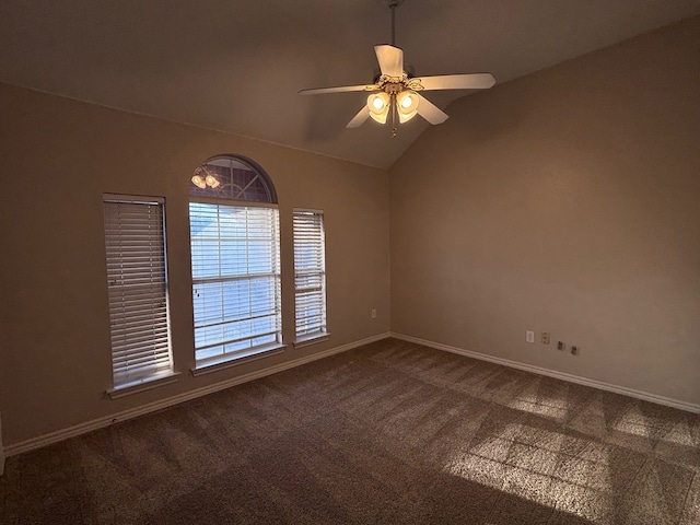 spare room with lofted ceiling, dark colored carpet, a ceiling fan, and baseboards