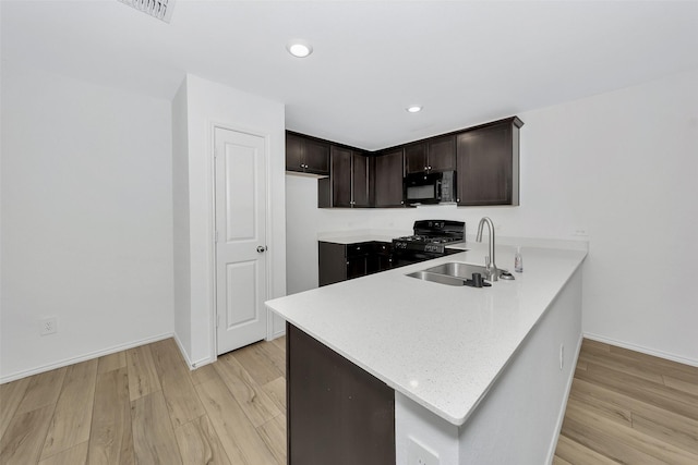 kitchen with dark brown cabinetry, sink, light hardwood / wood-style flooring, and black appliances