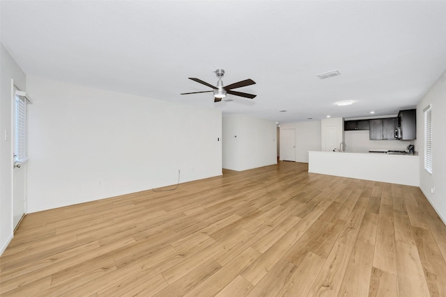 unfurnished living room featuring ceiling fan, sink, and light hardwood / wood-style floors