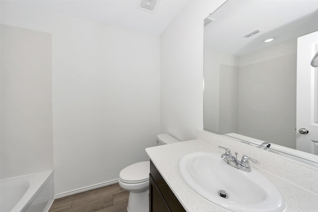 bathroom featuring vanity, a bathtub, wood-type flooring, and toilet