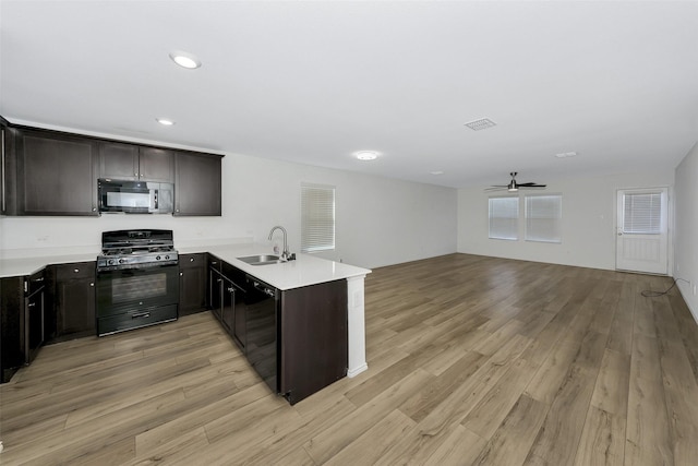 kitchen featuring black appliances, sink, kitchen peninsula, dark brown cabinets, and light wood-type flooring