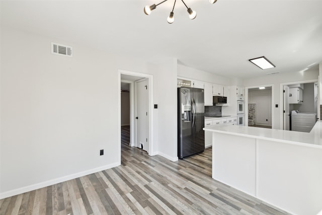 kitchen featuring stainless steel refrigerator with ice dispenser, light hardwood / wood-style flooring, white double oven, black electric stovetop, and white cabinets