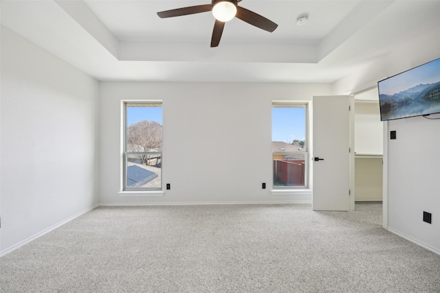 carpeted spare room featuring ceiling fan and a raised ceiling