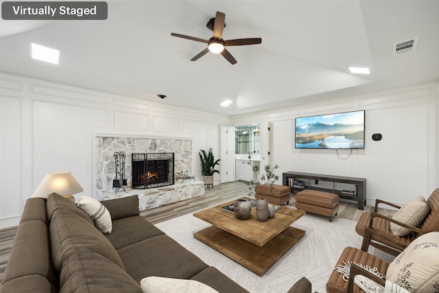 living room featuring light hardwood / wood-style flooring, a fireplace, high vaulted ceiling, and ceiling fan