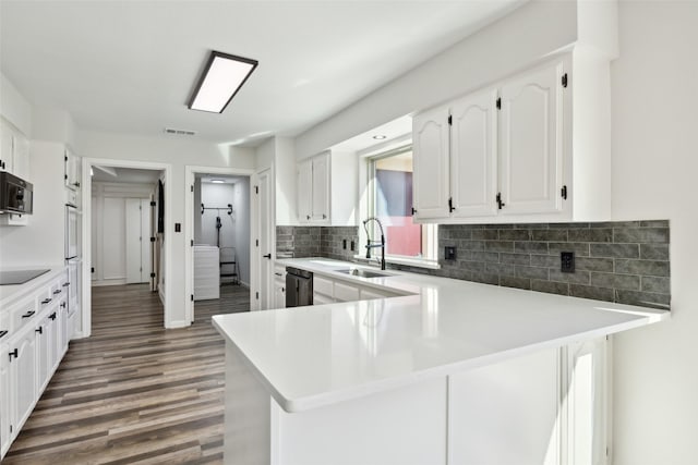 kitchen with white cabinetry, dishwashing machine, decorative backsplash, black electric stovetop, and kitchen peninsula