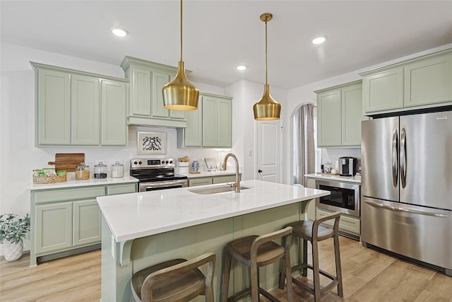 kitchen featuring sink, a breakfast bar area, light wood-type flooring, stainless steel appliances, and light stone countertops