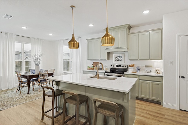 kitchen with light stone counters, light hardwood / wood-style floors, sink, and stainless steel range with electric cooktop