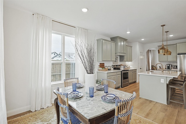 kitchen featuring pendant lighting, a kitchen island with sink, gray cabinetry, a kitchen bar, and stainless steel range with electric cooktop