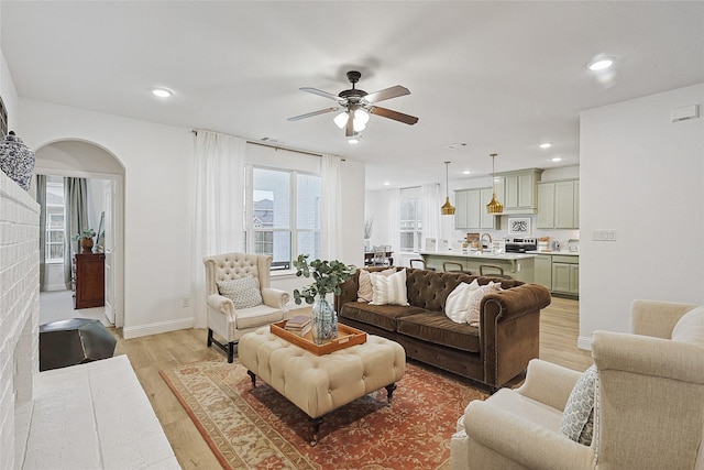 living room featuring sink, light hardwood / wood-style flooring, ceiling fan, and plenty of natural light