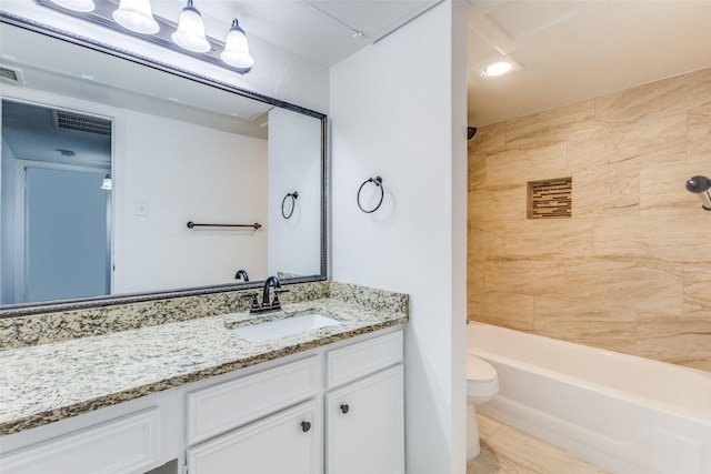 full bathroom featuring vanity, tiled shower / bath combo, and toilet