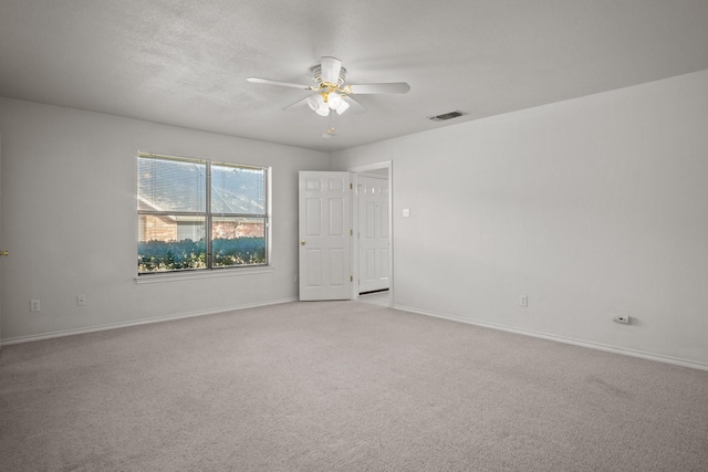 spare room with ceiling fan, light carpet, and a textured ceiling