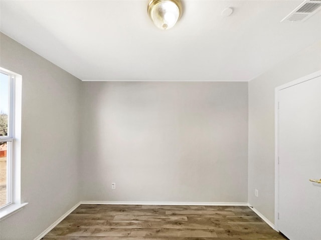 empty room featuring plenty of natural light and dark hardwood / wood-style floors