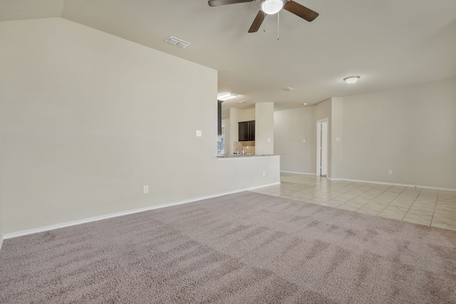 empty room with ceiling fan, light colored carpet, and vaulted ceiling